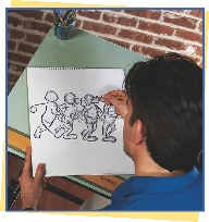 photograph of a man drawing sketches of cartoon characters on a pad